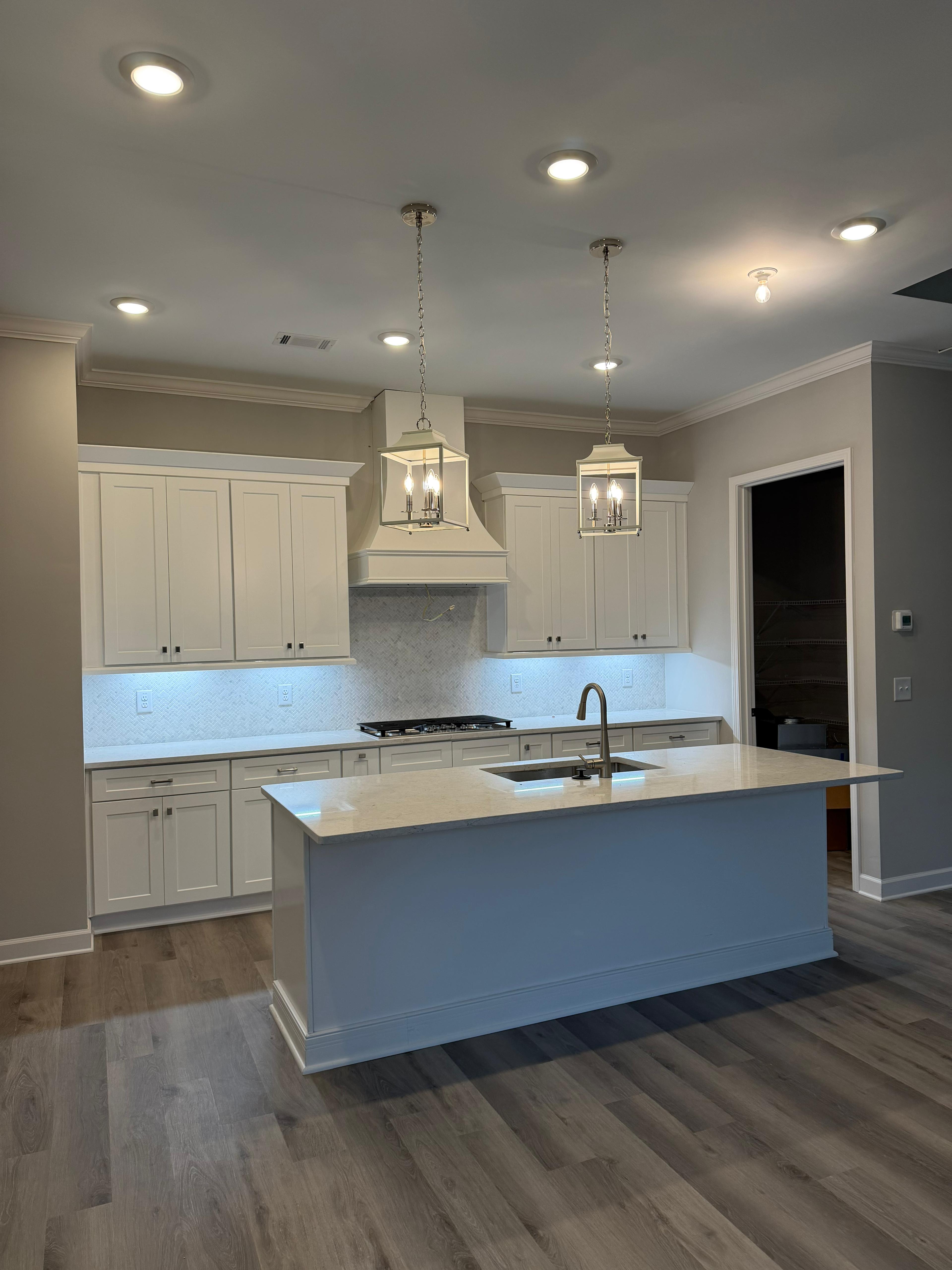 White kitchen cabinets with a contrasting island, cabinet hardware and pendant lights
