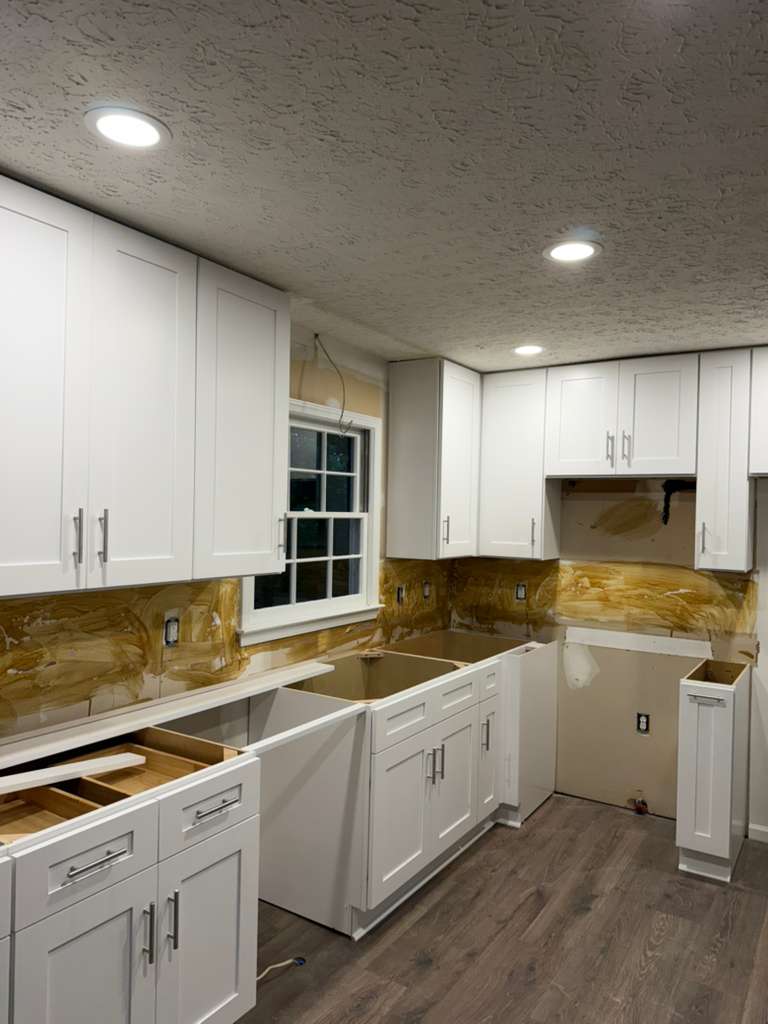 White kitchen cabinets and hardware during renovation, before countertops and final finishing.