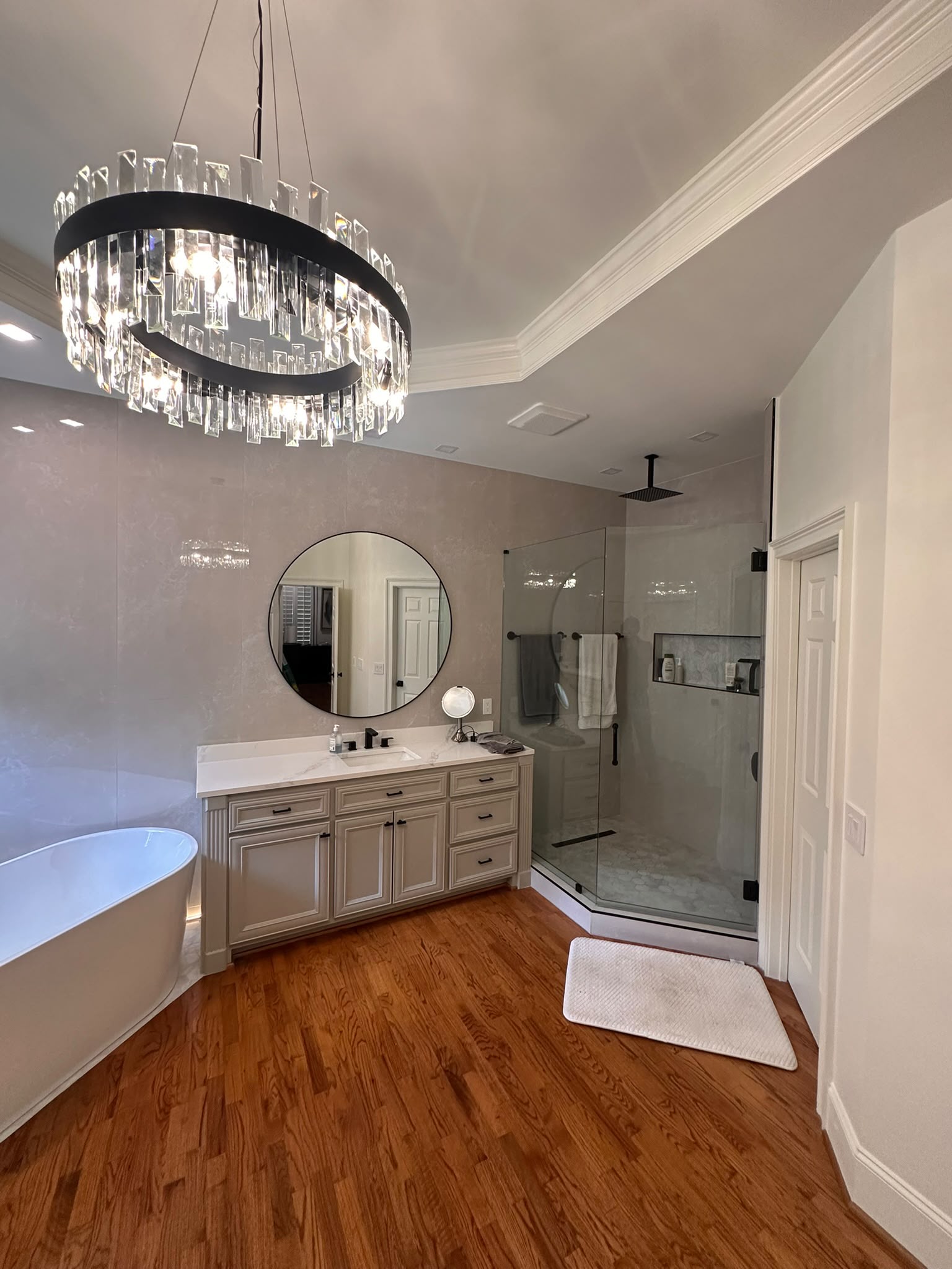 Bathroom with soaking tub, vanity, glass shower and statement chandelier.