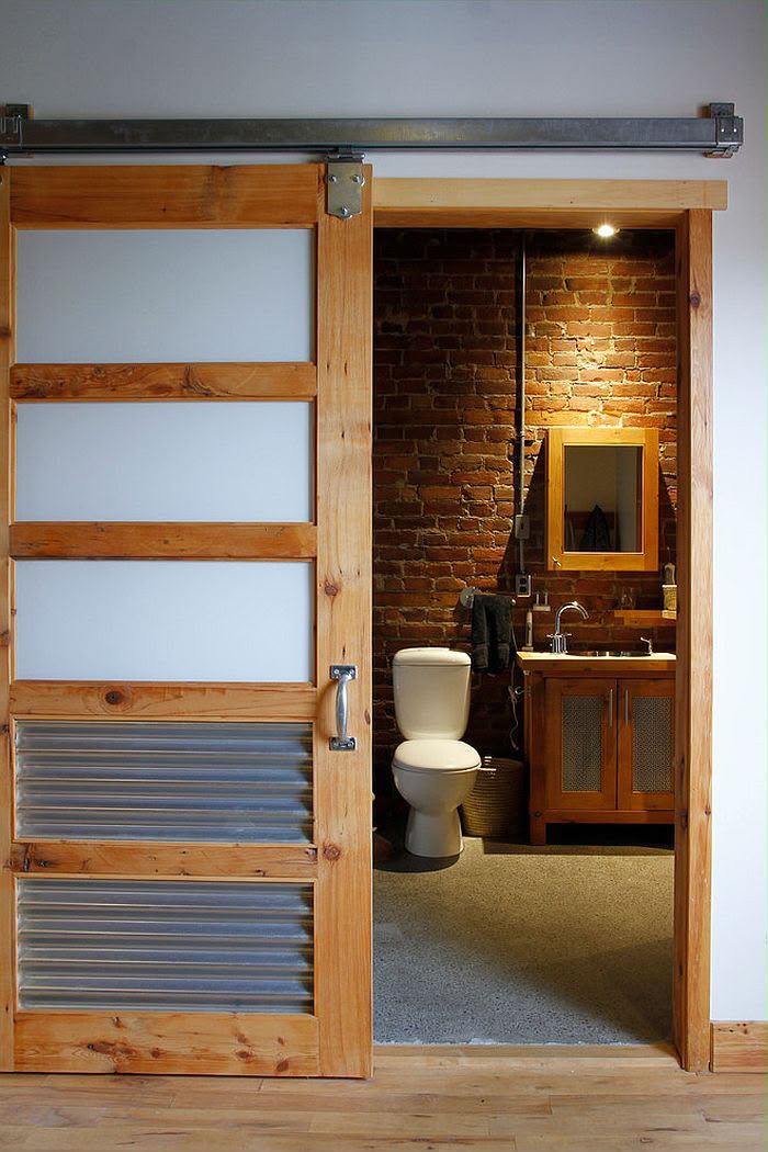 Wood sliding door opening to a bathroom with a warm wood vanity.